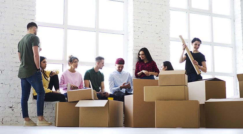 Movers disassembling office desks and loading office equipment into a moving van